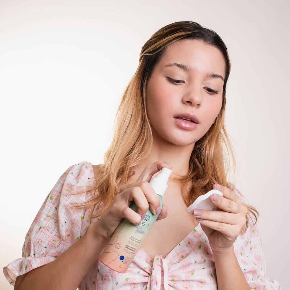 Mulher jovem preparando um algodão com a Água Micelar Teen LOA, demonstrando o uso do produto na rotina de cuidados com a pele.